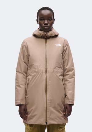 Person iført en knælange beige North Face jakke med hætte, frontlynlås og lynlåslommer, vendt fremad mod en ensfarvet baggrund.