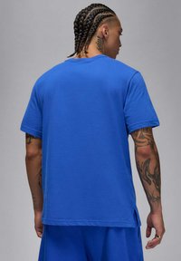 T-shirt in cotone blu con colletto a girocollo, maniche corte e spacchi laterali. Presenta una texture liscia e dettagli di cucitura minimi.