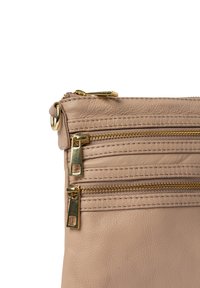 Beige lædertaske med tre lynlåslommer, der har hardware i guldfarve og tekstureret søm langs sømmene. Glat udvendig finish.
