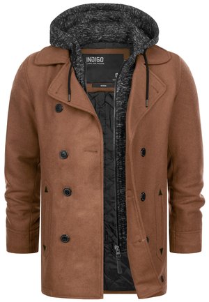 Manteau en laine double boutonnage marron avec boutons noirs superposé sur un sweat à capuche zippé noir et gris avec cordon de serrage.