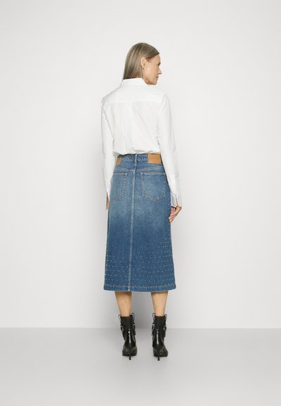 Blaue Denim-Midirock mit Nietenverzierungen am Saum. Verfügt über ein braunes Lederetikett an der Taille und zwei aufgesetzte Taschen auf der Rückseite.