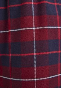 Rood en marineblauw geruit stof met een zachte textuur, waarin witte en lichtrode accenten een geblokt patroon vormen.