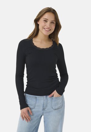 Top nero a maniche lunghe con texture a coste e scollatura rotonda rifinita in pizzo, abbinato a jeans blu chiaro a vestibilità ampia.