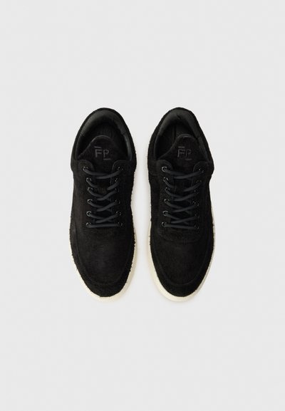 Svart semsket sneakers med hvite gummisåler, med svarte lisser og rund tådesign. Logo preget på tungen.
