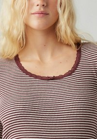 Bordeaux gestreepte top in bruin en crème met een geschulpte bordeaux décolleté. Katoenen materiaal met een gestructureerde oppervlakte. Eenvoudig ontwerp, nauwsluitende snit.
