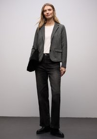 Szary teksturowany blezer o dopasowanym kroju, noszony na białej bluzce, zestawiony z czarnymi jeansami o szerokich nogawkach i czarnymi botkami za kostkę.