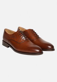 Chaussures habillées en cuir marron avec une finition brillante, présentant des détails perforés complexes, un design classique à lacets et un bout arrondi.