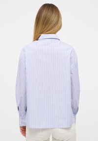 Gestreepte blouse met lange mouwen, lichtblauwe en witte verticale strepen, knoopmanchetten, iets afgeronde zoom, kraag. Glad stofoppervlak.