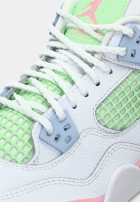 Κοντινό πλάνο λευκού και παστέλ πράσινου αθλητικού παπουτσιού με λευκά κορδόνια, μπλε οπές και ροζ λογότυπο στη πράσινη γλώσσα.