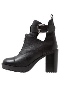 Czarny skórzany botek za kostkę z grubym, wysokim obcasem, bocznym zamkiem błyskawicznym i regulowanym paskiem z klamrą. Teksturowana powierzchnia z gumową podeszwą.