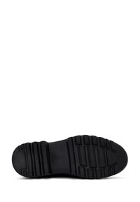 Zwarte schoenen met een gestructureerde rubberen zool, met een geribbeld patroon voor grip. Het ontwerp is functioneel met een ronde neus en een platte profiel.