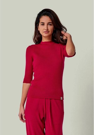 Rotes geripptes Strickoberteil mit kurzen Ärmeln und hohem Ausschnitt, das am Saum ein kleines Logo-Detail und eine enganliegende Passform hat.