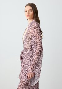 Kimono leggero e trasparente di colore lilla con un motivo a leopardo; presenta maniche lunghe e una vita legata. Texture liscia.