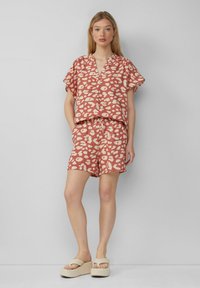 Kurzärmeliges Oberteil mit pinkem Muster und passenden Shorts, aus leichtem Material gefertigt, mit unregelmäßigen weißen Punkten und einem elastischen Bund.