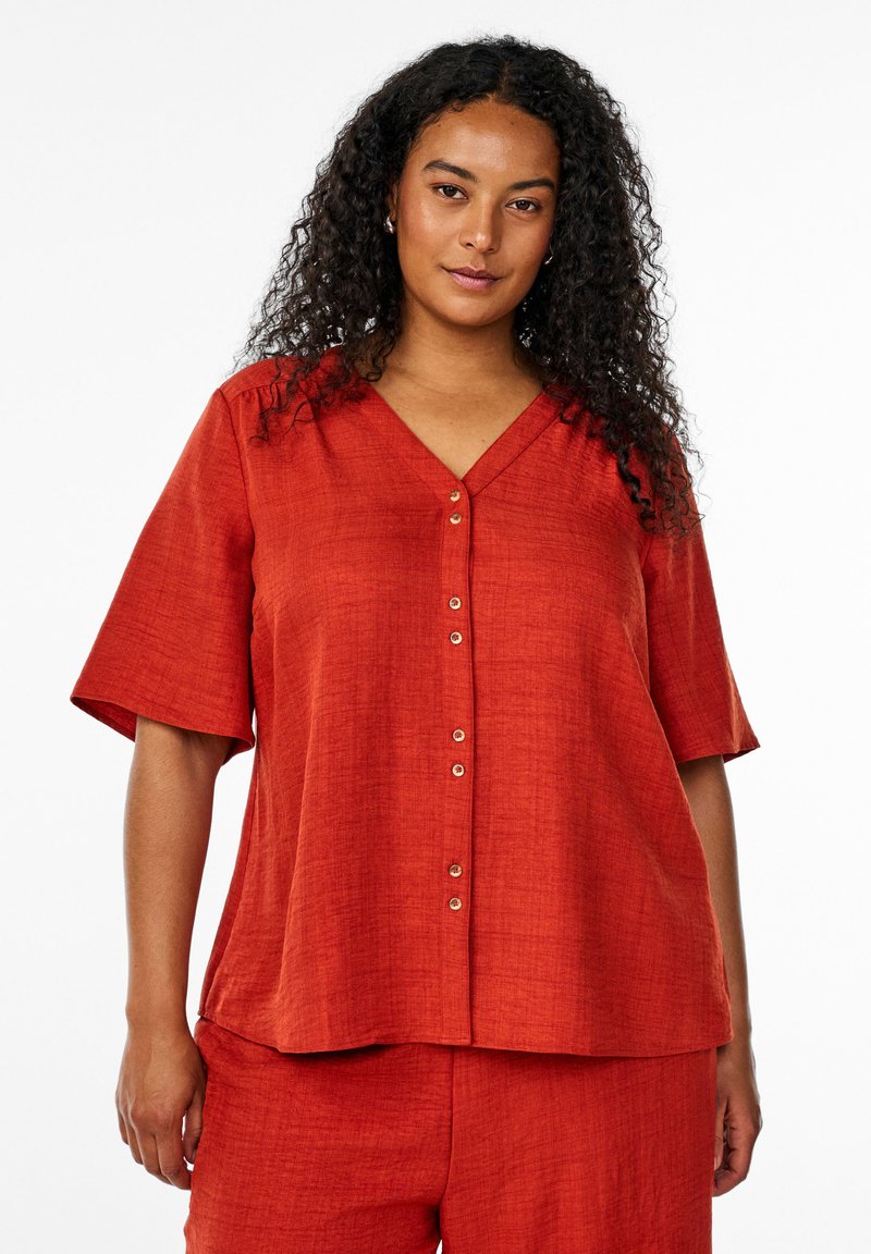 Blusa rossa a maniche corte con scollatura a V e chiusura a bottoni, realizzata in un tessuto testurizzato. Vestibilitàampia con orlo dritto.