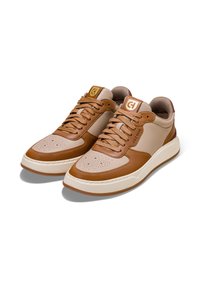 Białe skórzane sneakersy z beżowymi akcentami, okrągłym noskiem, perforowanym przodem, kontrastującą podeszwą oraz złotym logo na języku.