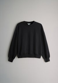 Must puuvillasegust dressipluus, millel on ümmargune kaelus, pikad varrukad ning soonikkoes mansetid ja ääred. Sile tekstuur.