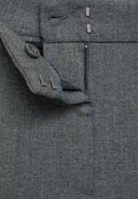 Šedé strukturované kalhoty s knoflíkovým zapínáním, kapsou na zip a elegantními, nenápadnými kovovými doplňky podél pasu.