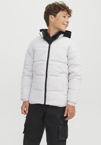 Vit uppblåsbar jacka med dragkedja fram, svarta detaljer och quiltad design. Den har en huva och elastiska ärmslut för en säker passform.