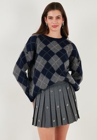 Navy and gray argyle-pattern sweater made of soft material, paired with a pleated gray skirt featuring patterned floral accents.