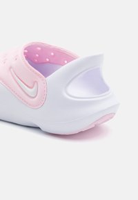 Rožinė ir balta Nike šlepetė, su lygiu, tekstūruotu paviršiumi, suapvalintu užpakaliu, šoninėmis angomis ir ryškiu swoosh logotipu.
