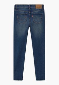 Vaqueros de denim azul oscuro con una cintura de altura media, que cuentan con dos bolsillos traseros y un dobladillo ligeramente deshilachado para un look informal.