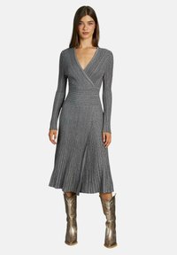 Rochie gri, cu dungi, cu mânecă lungă, design înfășurat și tiv evazat, asortată cu cizme argintii metalizate până la genunchi. Fără modele sau accente vizibile.