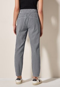 Pantalons rayés avec un design ajusté, une taille élastique et deux poches arrière. La palette de couleurs comprend des rayures bleu marine et blanches.