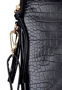 Czarna teksturowana skórzana torba z wzorem skóry krokodyla. Złote metalowe zapięcie i dwa czarne skórzane frędzle zawieszone.