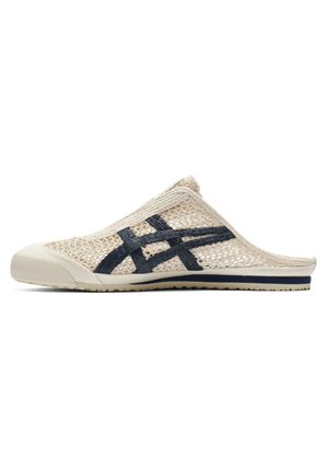 Beiger Slipper aus Mesh mit schwarzen überkreuzten Streifen und Gummisohle, entworfen für legere Trageweise und Atmungsaktivität.