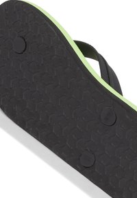 Svart flip-flop sula med ett strukturerat greppmönster, med en livlig grön kant. Lättviktig design med tydliga vänster- och högermarkeringar.
