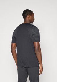 Μαύρη αθλητική μπλούζα με υφή και ριγέ σχέδιο στους ώμους. Έχει κοντό μανίκι και κλασική στρογγυλή λαιμόκοψη, κατασκευασμένη από ελαφρύ ύφασμα.