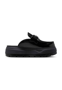 Sandalias de plataforma negras hechas de charol, con punta redonda, acento de hebilla y suela gruesa texturizada con profundas ranuras.