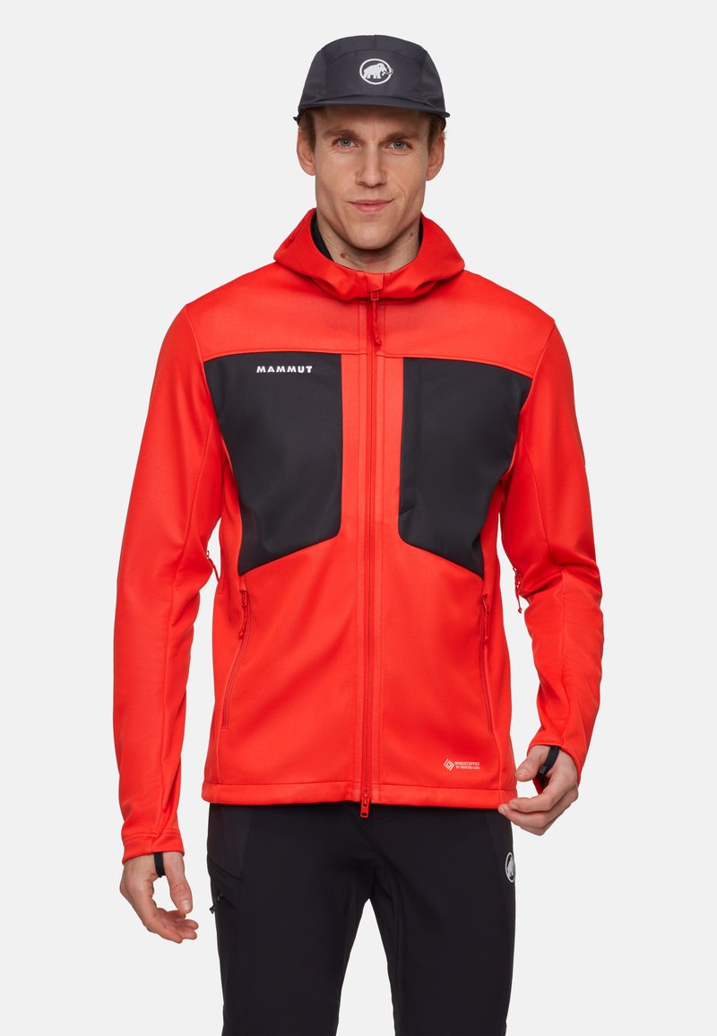 Rød softshell-jakke med sorte accenter, lynlås-lommer og justerbar hætte. Lavet af letvægtsmateriale til udendørs aktiviteter.