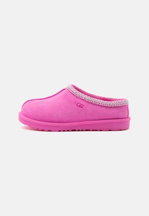 Chausson slip-on UGG rose avec dessus en daim, logo brodé, bordure tressée autour de l'ouverture et semelle en caoutchouc, vu de côté.