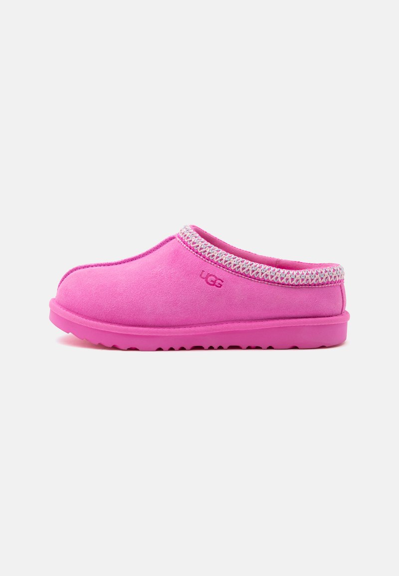 Chausson slip-on UGG rose avec dessus en daim, logo brodé, bordure tressée autour de l'ouverture et semelle en caoutchouc, vu de côté.