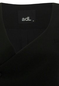 Blazer nero con scollatura a V, tessuto liscio, chiusura con un solo bottone e un'etichetta bianca che recita "adL".