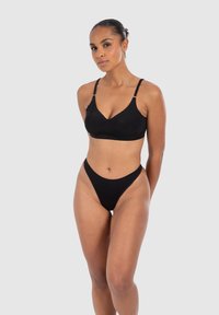 Soutien-gorge noir sans coutures avec bretelles ajustables et thong taille haute assorti. Tissu lisse avec un design minimaliste pour une apparence élégante.