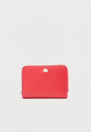 Πορτοφόλι από κόκκινο δέρμα με λεία υφή, κλείσιμο με φερμουάρ και μικρό λευκό μεταλλικό λογότυπο στο μπροστινό μέρος. Ορθογώνιο σχήμα.