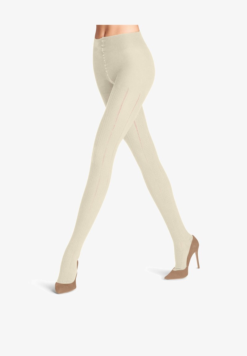 Knielange Strumpfhosen aus leichtem beigem Strick, mit vertikalen Rippungen und dezenten rosa Nahtdetails. Getragen mit taupefarbenen Heels.