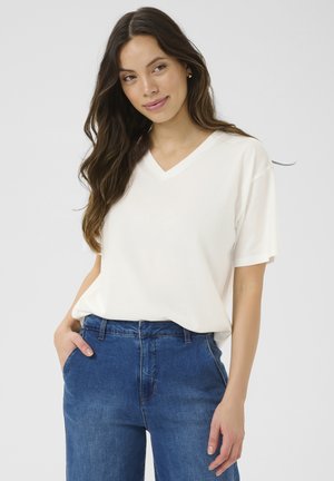 V-neck, short-sleeve t-shirt in off-white, made from soft fabric. Paired with high-waisted blue denim jeans. Simple design, relaxed fit.