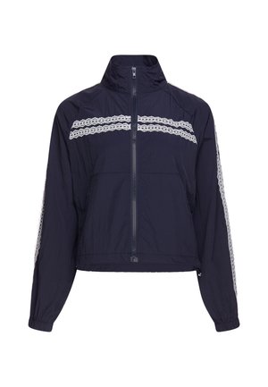 Marineblaue Jacke mit Reißverschluss, hohem Kragen und weißen spitzenähnlichen Streifen über Brust und entlang der Ärmel, elastischen Bündchen und Vordertaschen.