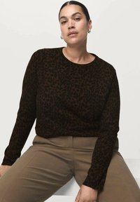 Suéter de punto con estampado de leopardo marrón, con escote redondo y mangas largas, combinado con pantalones ajustados de color marrón claro. Textura suave y diseño ajustado.