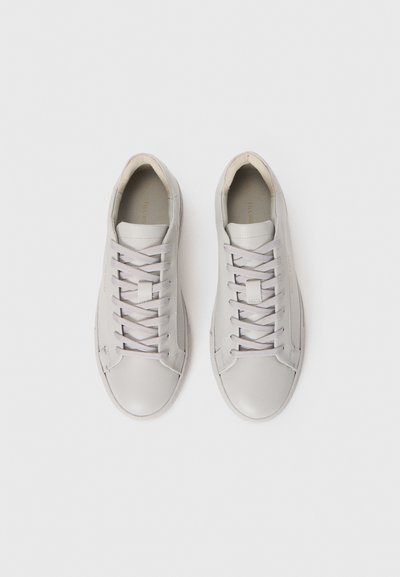 Kerge hallid madalad nahksneakerid paeltega, vaadatuna ülalt, valgel taustal.