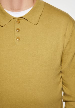 Senfgelbes Polohemd aus geripptem Stoff mit Kragen und einer Drei-Knopf-Leiste. Glatte Textur mit minimalistischem Design.