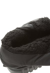 Botte d'hiver noire avec un intérieur doux doublé de fourrure. Le matériau extérieur est lisse, et la semelle est équipée de crampons texturés pour l'adhérence.