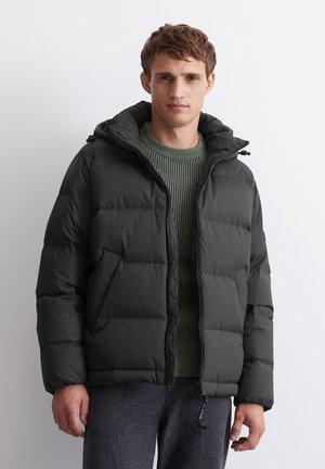 Black puff jacket with a hood, ribbed green sweater underneath, featuring a zipper front and stitched pattern. Informal fit, casual design.
