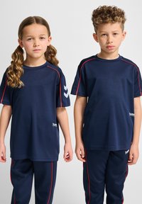 Marina atletiska t-shirts och byxor med röda accenter; tyget verkar vara lätt och andas; har logotyp och chevrondesign på ärmarna.