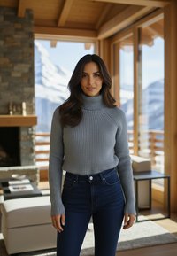 Szary prążkowany golf z długimi rękawami, zestawiony z ciemnoniebieskimi, wysokim stanem jeansami, w jasnym, przestronnym drewnianym wnętrzu.