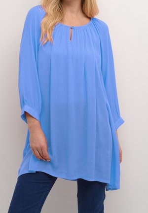 Lyseblå, løstsiddende tunika med trekvartlange ærmer, der har en udskæring med knaphul og blødt, tekstureret stof. Blidt udvidet silhuet.